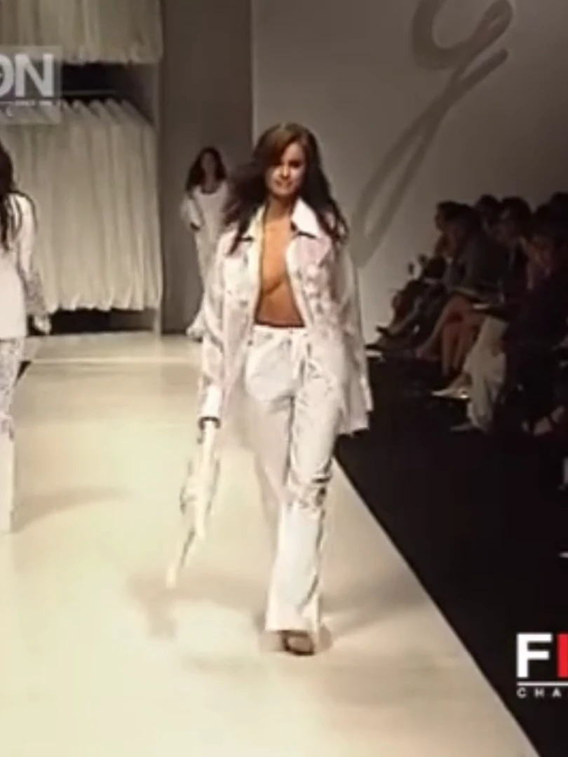 Runway model smiles happily as one of her tits slowly pops out of the open shirt